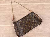 a louis vuitton wrist bag on a wooden floor