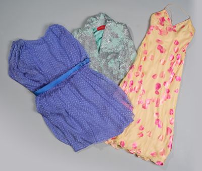 trois robes sont suspendues à un cintre posé sur une surface grise