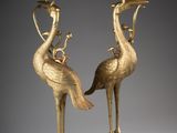 pair of brass candlesticks with birds on top of them