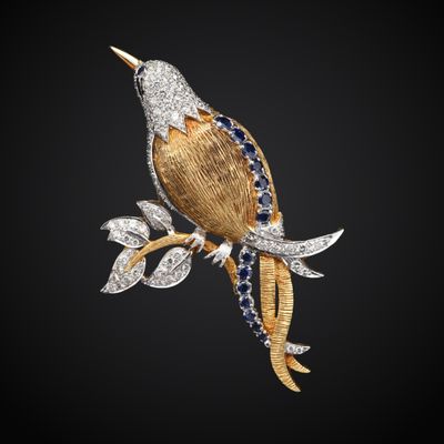 une broche en forme d'oiseau en or et diamants, posée sur une branche