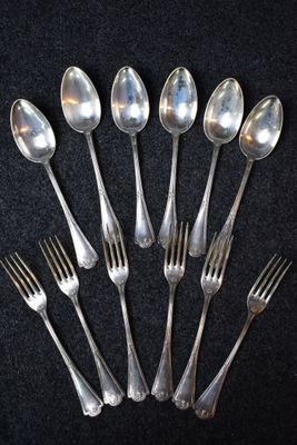 six cuillères et six fourchettes en argent sont disposées en cercle