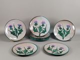 quatre assiettes ornées de motifs de chardons, posées sur une table