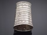 a silver cuff bracelet with geometric designs on a black surface