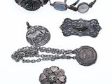 an assortment of silver jewelry on a white surface with a white background