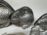 two fish shaped metal objects on a white surface