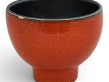 a red bowl with a black rim sitting on a white surface