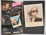 Barbie, la poupée grandeur nature, se trouve dans une boîte sur laquelle figure la photo d'une femme portant des lunettes de soleil