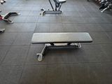 un banc au milieu d'une salle de sport, entouré d'autres appareils de musculation