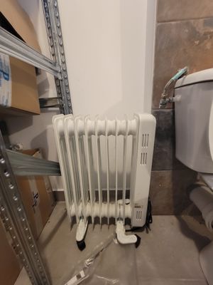 a white toilet sitting next to a white radiator in a bathroom