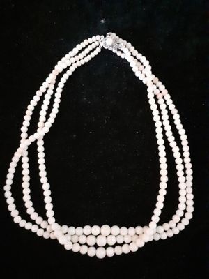 a close up of three strands of pearls on a black background