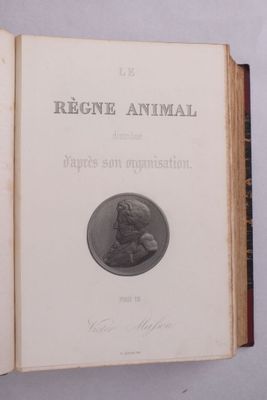un vieux livre posé sur une table, avec une pièce de monnaie dessus
