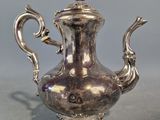une théière ancienne en argent, munie d'une anse, posée sur une table