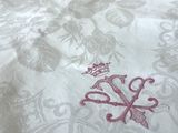 un gros plan d'un lit recouvert d'une couette blanche sur laquelle est posée une couronne rouge