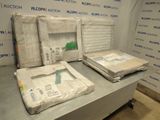 Plusieurs cartons contenant des matelas sont empilés sur une table devant un mur.