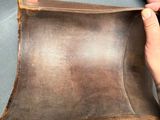 a person that is holding a brown leather case