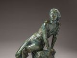 l'image d'une statue de bronze représentant une femme assise sur un rocher