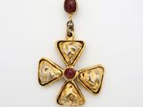 un gros plan d'un pendentif en forme de croix en or orné d'une pierre rouge