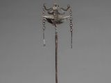 a silver sculpture of a bird on top of a pole