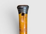 an old wooden stick with a black handle on a white surface