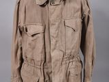 une veste marron posée sur un mannequin, devant un fond gris