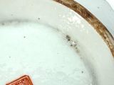 a white plate with a brown border and a red stamp on it
