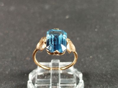 a ring with a blue topaz stone on a clear stand