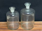 two empty glass bottles on a wooden table with a black background