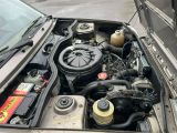un moteur de voiture dont le capot est ouvert, garé dans la rue
