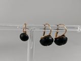 a pair of black and gold earrings on a clear stand
