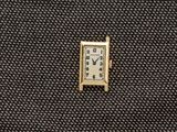 une petite horloge carrée posée sur un morceau de tissu