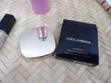 a bottle of perfume next to a compact mirror and a bottle of nail polish on a table