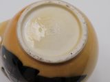 a close up of a yellow and black vase on a white surface