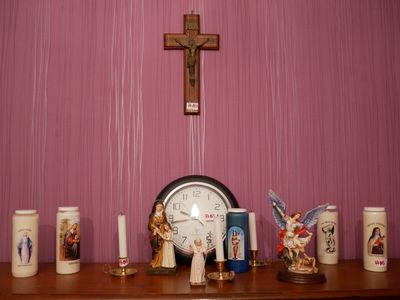 une étagère en bois sur laquelle sont posés une horloge, des bougies et des figurines