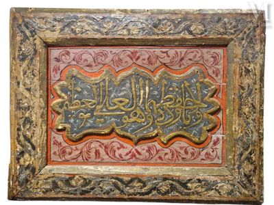 calligraphie arabe en or et rouge sur un cadre en bois