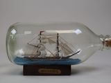 un bateau dans une bouteille, posé sur un socle en bois