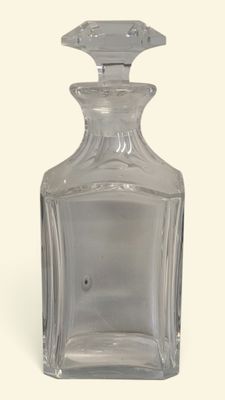 une bouteille en verre transparent avec un bouchon argenté, posée sur une surface blanche