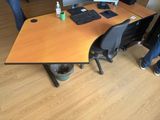 two people standing around a desk with a computer on it
