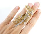 a woman ' s hand holding a gold and diamond ring