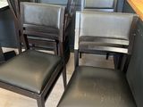 four black leather dining chairs sitting next to each other on a wooden floor