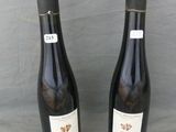 two bottles of wine are sitting on a table with a gray background