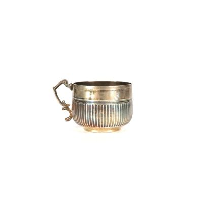 une coupe ancienne en argent avec une anse, sur fond blanc