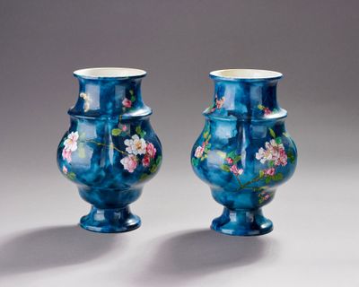 une paire de vases bleus ornés de fleurs, posés sur une surface blanche