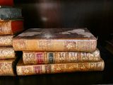 une pile de vieux livres posée sur une étagère dans une pièce