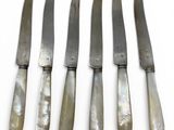 five knives are lined up in a row on a white surface