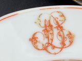 an orange and white plate with a monogram on it