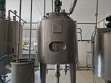 Plusieurs cuves en acier inoxydable sont alignées dans une grande salle