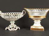 une paire de vases blancs et dorés posés sur des socles, sur fond noir