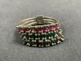 a close up of a silver ring with pink and green stones