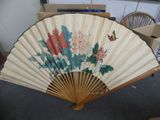a fan with flowers and butterflies on it in a room