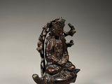 bronze statue of a woman sitting on a rock with a bird in her hand